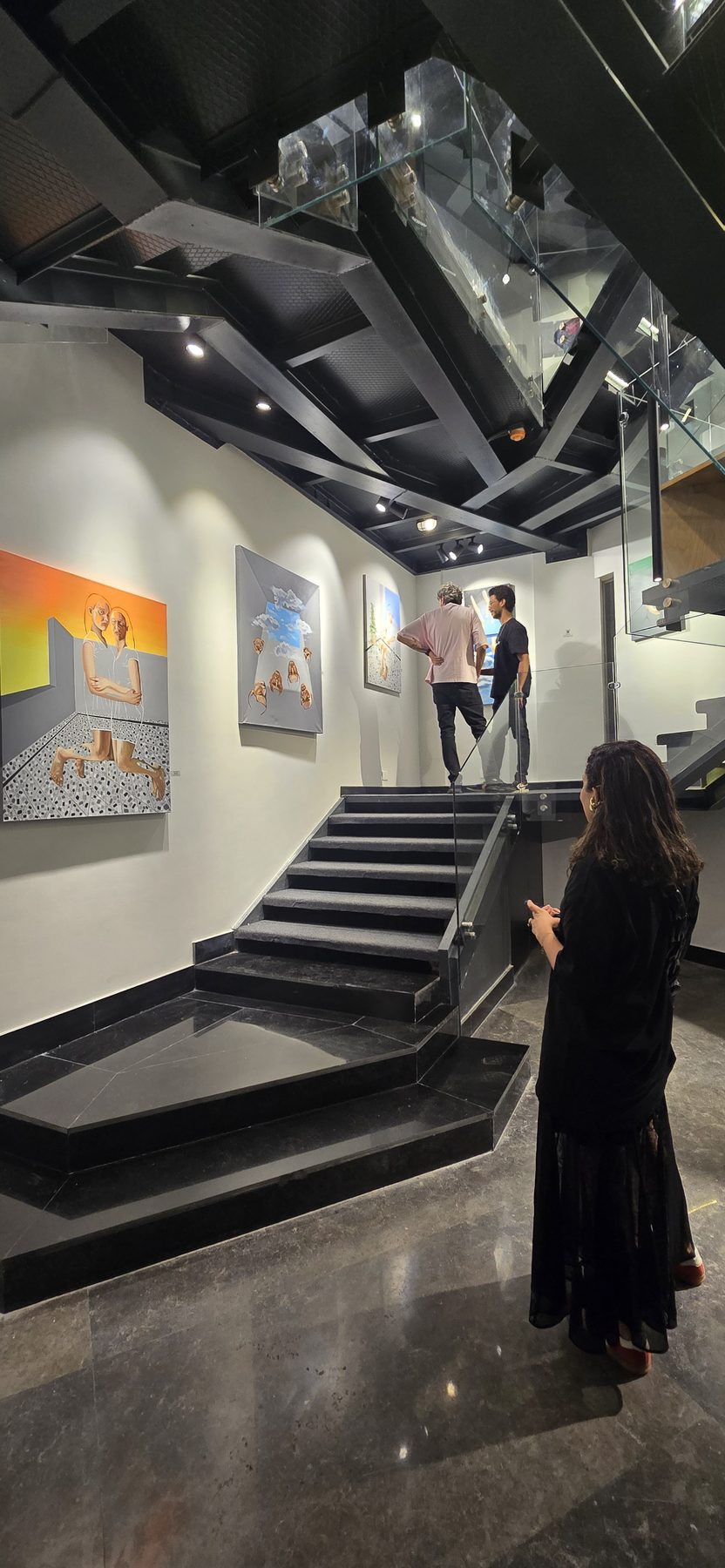 A visitor looks at paintings along the gallery's black steel stairwell